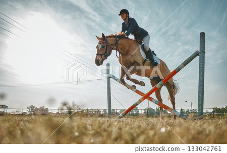 Training, jump and woman on a horse for a course, event or show on a field in Norway. Equestrian, jumping and girl doing a horseback riding obstacle during a jockey race, hobby or sport in nature 133042761