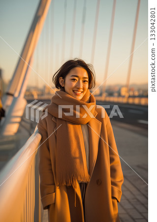 黃昏時分，一位女子在橋上微笑 | 她自然的笑容和溫暖的氣質，在冬日的城市景觀中格外醒目 133042801