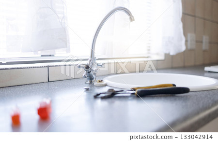 Faucet, tools and plumbing with maintenance in kitchen, repairs on sink with handyman trade and manual labor. Water tap, counter and home renovation with DIY, vocation skills and steel with service Faucet, tools and plumbing with maintenance in kitchen, repairs on sink with handyman trade and manual labor. Water tap, counter and home renovation with DIY, vocation skills and steel with service 133042914