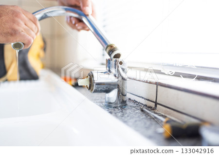 Plumber, faucet and plumbing, maintenance with man and manual labour, home renovation with trade and repairs. Construction, handyman in kitchen or bathroom sink with hardware, pipe and DIY vocation 133042916