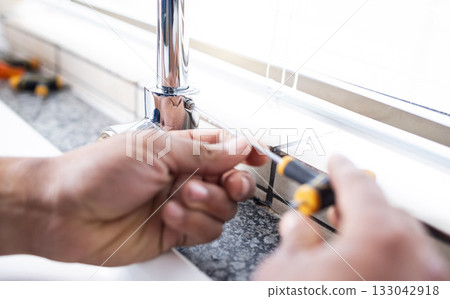 Plumbing man, faucet and hands with screw for building maintenance, renovation and service. Closeup handyman, tap and plumber tools of engineering contractor, upgrade pipeline system or mechanic work 133042918
