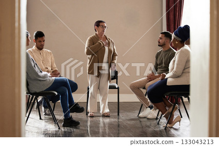 Support, old woman standing in group therapy and understanding, sharing feelings and talking in session. Mental health, grief or depression, men and women listening to therapist and sitting together. 133043213