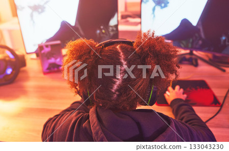 Back of girl, gamer and video game on computer in home, desk or online games of virtual competition. Female streamer, live streaming and gaming with headphones in neon lighting, esports tech or gen z 133043230