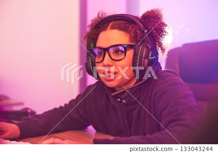 Video games, young girl and headset in home for esports, online rpg and virtual competition. Female gamer, computer streamer and gaming with headphones in neon lighting, live streaming tech and gen z 133043244