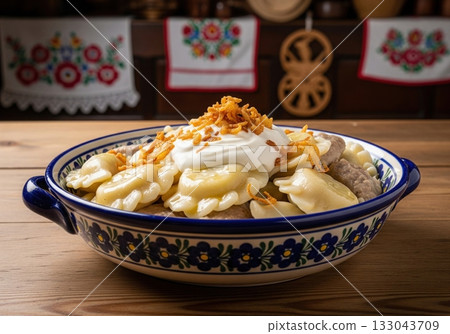 Traditional polish pierogi dumplings with sour cream and fried onion in a ceramic bowl 133043709