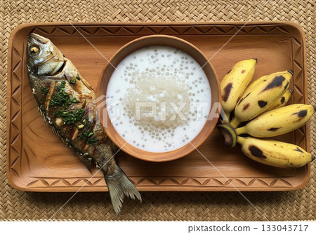 Traditional Sepik River meal with grilled fish sago pudding and bananas served on wooden tray 133043717