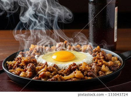 Sizzling filipino pork sisig served hot on cast iron skillet with raw egg yolk for pulutan Sizzling filipino pork sisig served hot on cast iron skillet with raw egg yolk for pulutan 133043724