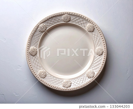 Classic dinnerware. Ceramic plate with a classic white design and floral border on a white background. Porcelain kitchenware. Close-up. Top view. Classic dinnerware. Ceramic plate with a classic white design and floral border on a white background. Porcelain kitchenware. Close-up. Top view. 133044203