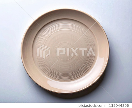 Fine dining. Ceramic plate with a classic beige design on a white background. Porcelain kitchenware. Close-up. Top view. Fine dining. Ceramic plate with a classic beige design on a white background. Porcelain kitchenware. Close-up. Top view. 133044206