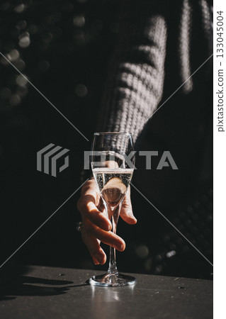 Hand Reaching for Champagne Glass in Sunlight Hand Reaching for Champagne Glass in Sunlight 133045004