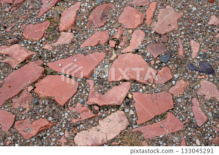 Old cobblestone pavement with uneven brown stones and patches of green grass. Ancient brick cobblestone tiles street with big stones Old cobblestone pavement with uneven brown stones and patches of green grass. Ancient brick cobblestone tiles street with big stones 133045291