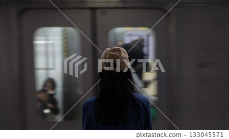 Blurred image of a woman standing on a train platform watching a train pass by. 133045571