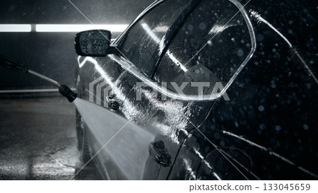 Side view of luxury sedan being rinsed under bright detailing lights Side view of luxury sedan being rinsed under bright detailing lights 133045659