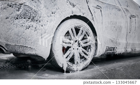 Close-up of car wheel covered with foam during detailed cleaning 133045667