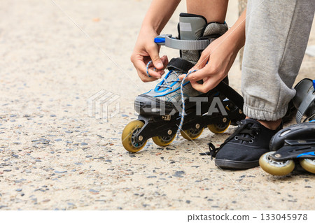 Woman putting on roller skates outdoor. Woman putting on roller skates outdoor. 133045978