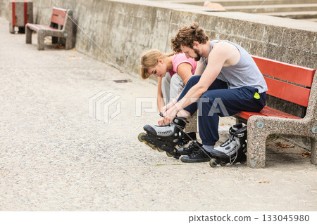 People friends putting on roller skates outdoor. People friends putting on roller skates outdoor. 133045980