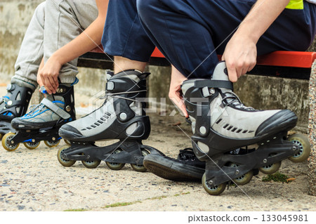 People friends putting on roller skates outdoor. People friends putting on roller skates outdoor. 133045981