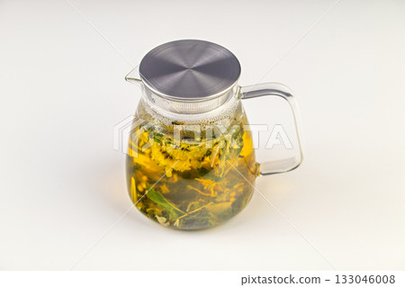 A glass pitcher with a lid and a handle filled with a tea blend A glass pitcher with a lid and a handle filled with a tea blend 133046008
