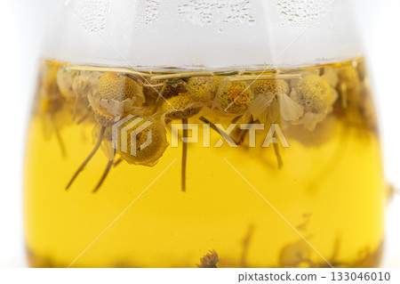 A glass of Chamomile tea with flowers floating in it A glass of Chamomile tea with flowers floating in it 133046010