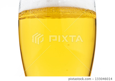 A glass of beer is shown with a lot of foam on top 133046014
