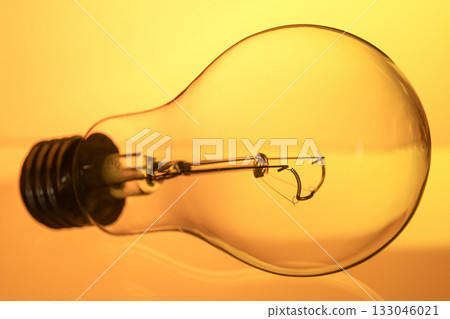 A light bulb is shown in a close up, with the bulb's filament visible A light bulb is shown in a close up, with the bulb's filament visible 133046021