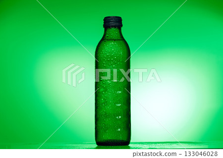 A green bottle of water is sitting on a table A green bottle of water is sitting on a table 133046028
