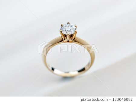A gold and white diamond ring with a small diamond in the center 133046092
