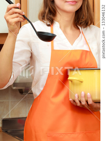 Woman with ladle and pot in kitchen Woman with ladle and pot in kitchen 133046132