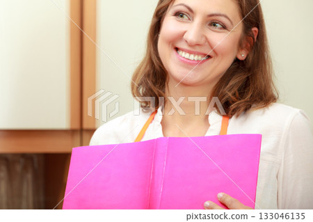 Housewife with cookbook in kitchen. 133046135