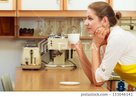 Mature woman drinking cup of coffee in kitchen. Mature woman drinking cup of coffee in kitchen. 133046141