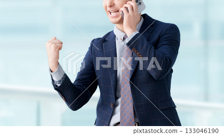 一名男子一邊用智慧型手機通話,一邊揮拳 一名男子一邊用智慧型手機通話,一邊揮拳 133046190