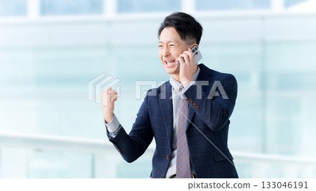 一名男子一邊用智慧型手機通話,一邊揮拳 一名男子一邊用智慧型手機通話,一邊揮拳 133046191