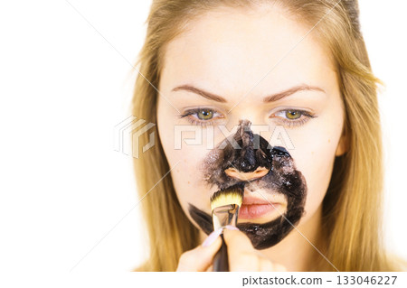 Girl being apply black mask to skin face Girl being apply black mask to skin face 133046227