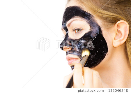 Woman applying black mud mask to face Woman applying black mud mask to face 133046248