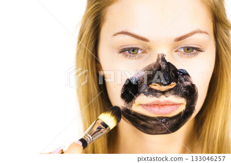 Girl being apply black mask to skin face Girl being apply black mask to skin face 133046257