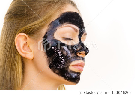 Woman applying black cleanser mask to face Woman applying black cleanser mask to face 133046263