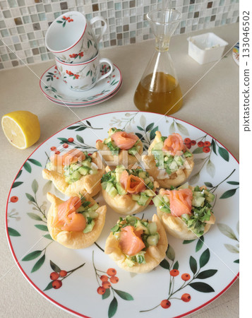 Pastry tartlet with cream cheese on plate. Appetizers made from cucumber, avocado, and salmon. Cooking at home. Mediterranean cuisine.  133046502