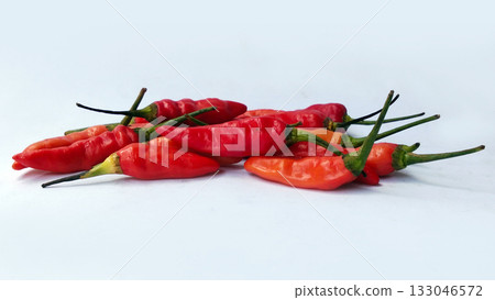 A bunch of bright red chilies with green stems arranged on a white background 133046572