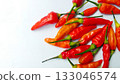 A bunch of bright red chilies with green stems arranged on a white background 133046574