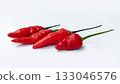 A bunch of bright red chilies with green stems arranged on a white background 133046576