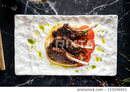 Grilled lamb chops with hummus and tomato slices Grilled lamb chops with hummus and tomato slices 133046601