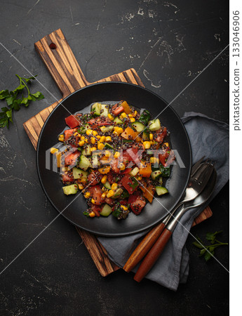 Quinoa salad black plate wooden cutting board fresh vegetables healthy diet vegetarian nutrition black background Quinoa salad black plate wooden cutting board fresh vegetables healthy diet vegetarian nutrition black background 133046906