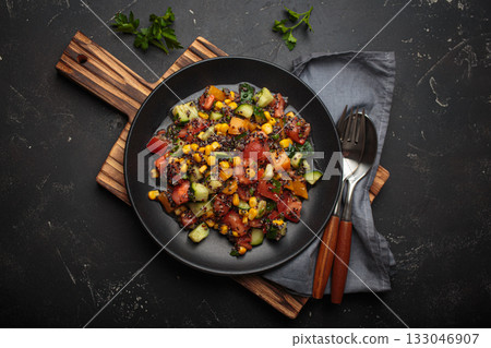 Quinoa salad black plate wooden cutting board fresh vegetables healthy diet vegetarian nutrition black background 133046907