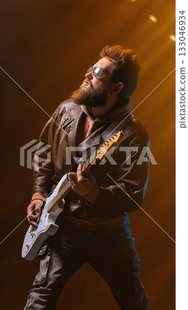 Bearded guitarist in sunglasses playing passionately under golden spotlight Bearded guitarist in sunglasses playing passionately under golden spotlight 133046934