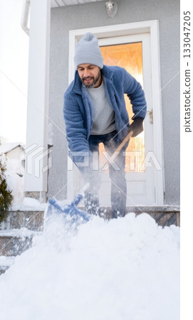 Man shoveling snow from stairs in cozy winter attire, creating a warm atmosphere during the winter solstice and embracing the season's beauty Man shoveling snow from stairs in cozy winter attire, creating a warm atmosphere during the winter solstice and embracing the season's beauty 133047205