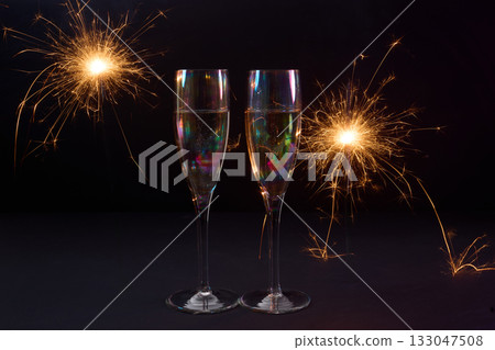 Sparkling Celebration. Two champagne glasses with bright sparklers against a dark background Sparkling Celebration. Two champagne glasses with bright sparklers against a dark background 133047508