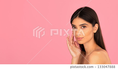 Young woman touching her cheek while posing against pink background Young woman touching her cheek while posing against pink background 133047888