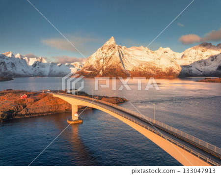 Aerial view of Hamnoy bridge and snowy rocks at sunrise Aerial view of Hamnoy bridge and snowy rocks at sunrise 133047913