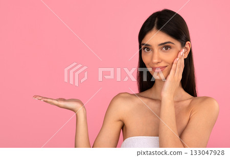 Smiling young woman touching cheek and showing open hand for copy space Smiling young woman touching cheek and showing open hand for copy space 133047928