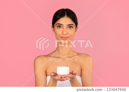 Young woman holding white cream jar in hands and looking at camera 133047930